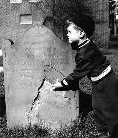 Vivian Maier capturing on film a child vandalizing a tombstone.  