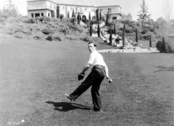 Buster Keaton playing catch on the lawn of his Beverly Hills estate.