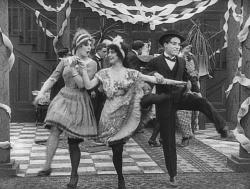 Charles Chaplin dances with two girls in Tango Tangles. Charles Chaplin dances with two girls in Tango Tangles.